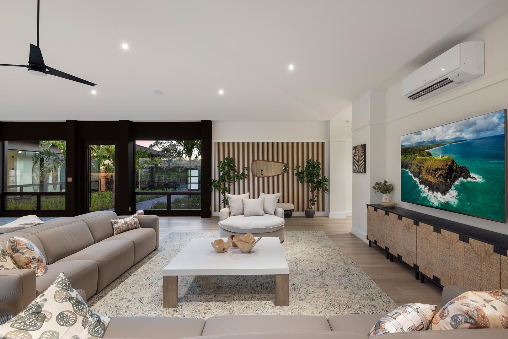 A living room with a couch , table , television and ceiling fan.