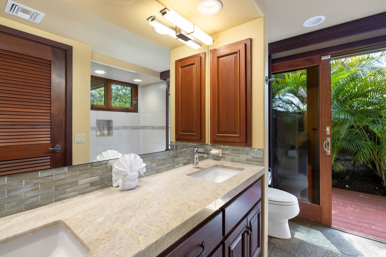 Bathroom with open door to a patio, wood cabinets, and light-colored countertop.