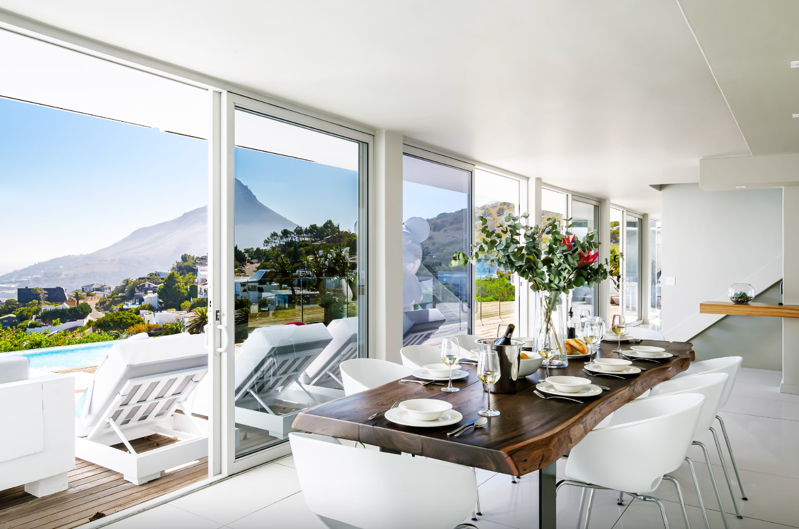Dining room with large windows, mountain view, long wood table set for dinner.