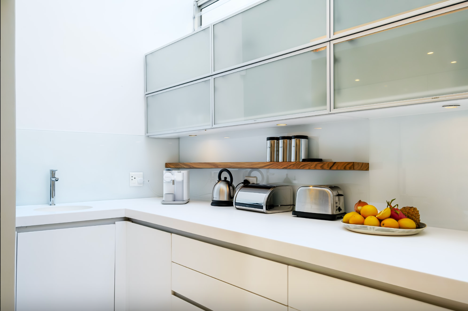 White modern kitchen with upper cabinets, countertop, and appliances.