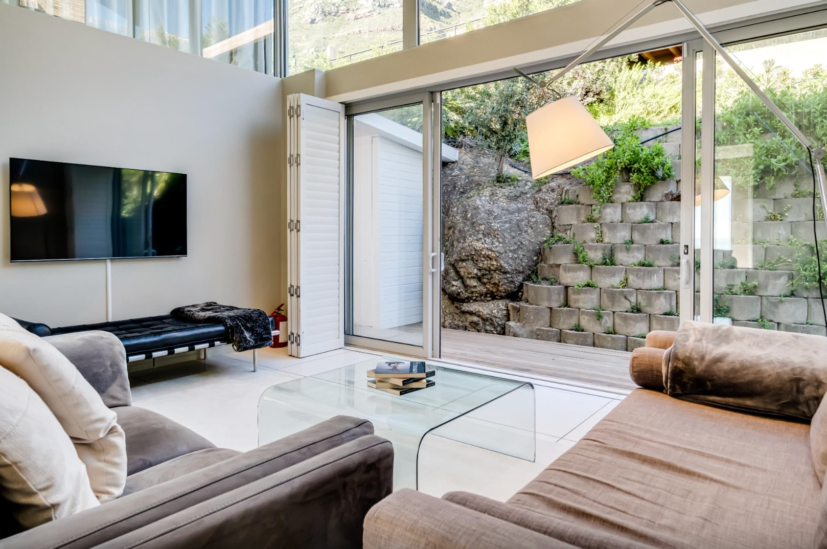 Living room with sliding glass door, modern furniture, and outdoor view of stone wall.