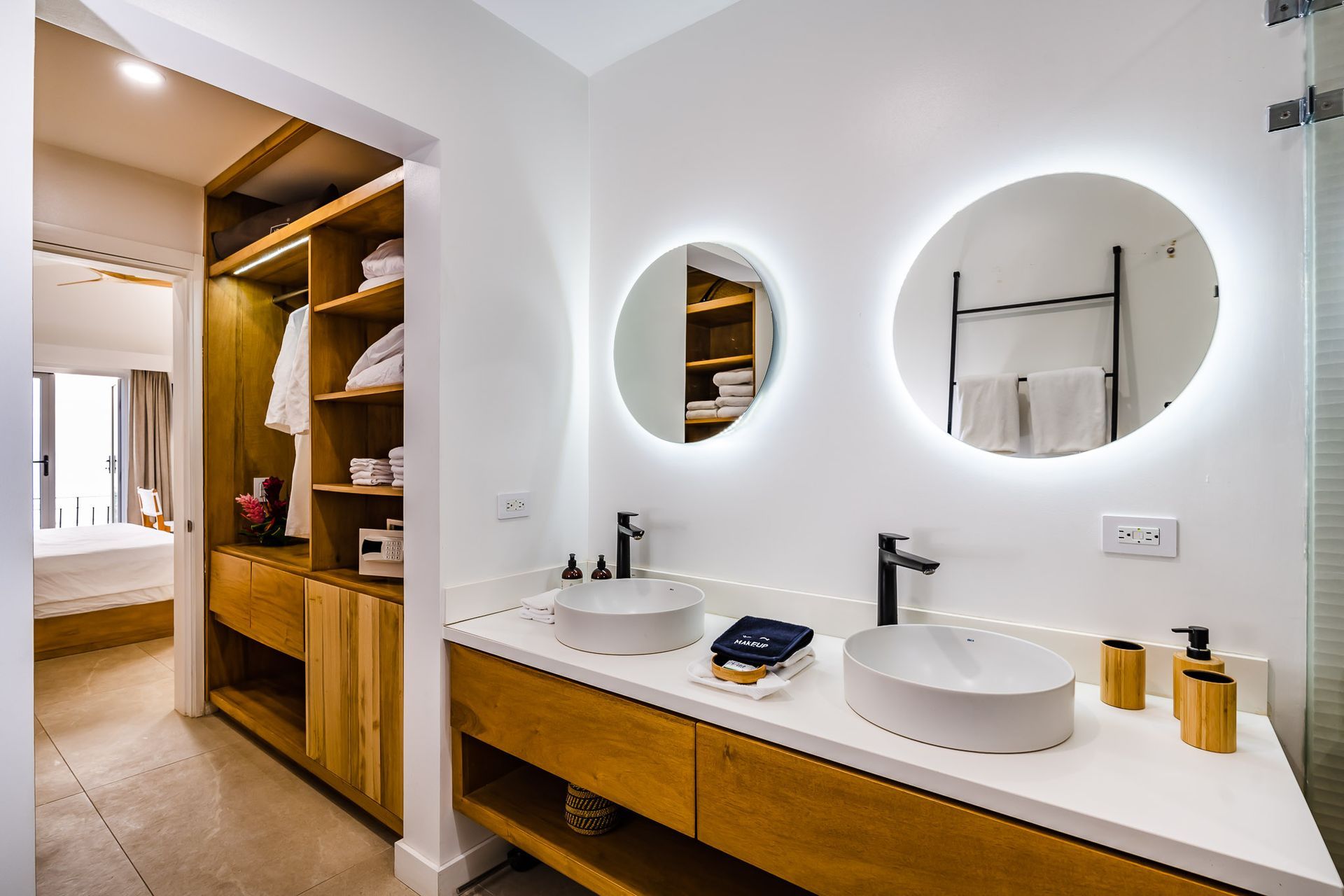 A bathroom with two sinks , two mirrors and a walk in closet.