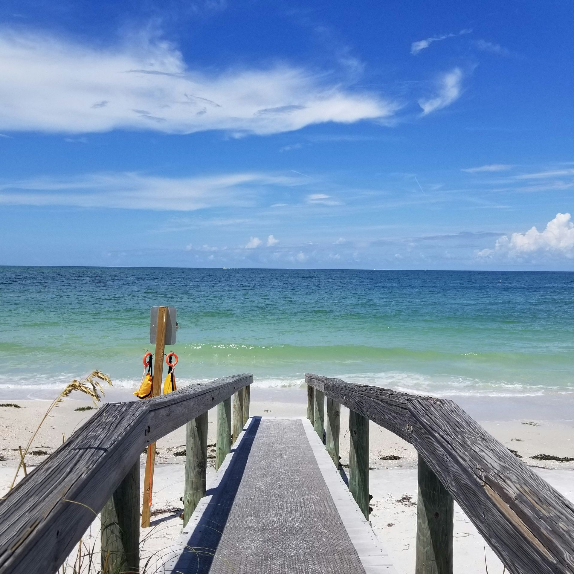 A wooden walkway leading to the ocean on a sunny day
