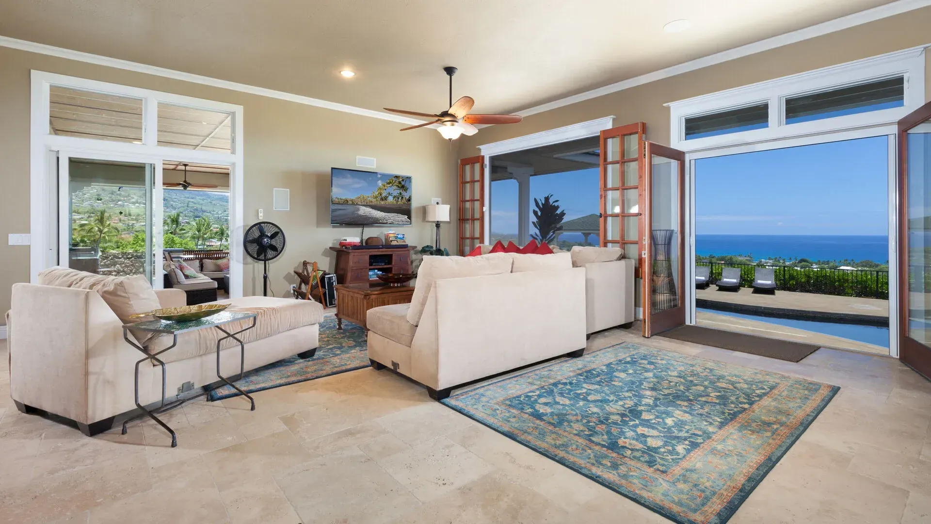 A living room with a view of the ocean and a ceiling fan.