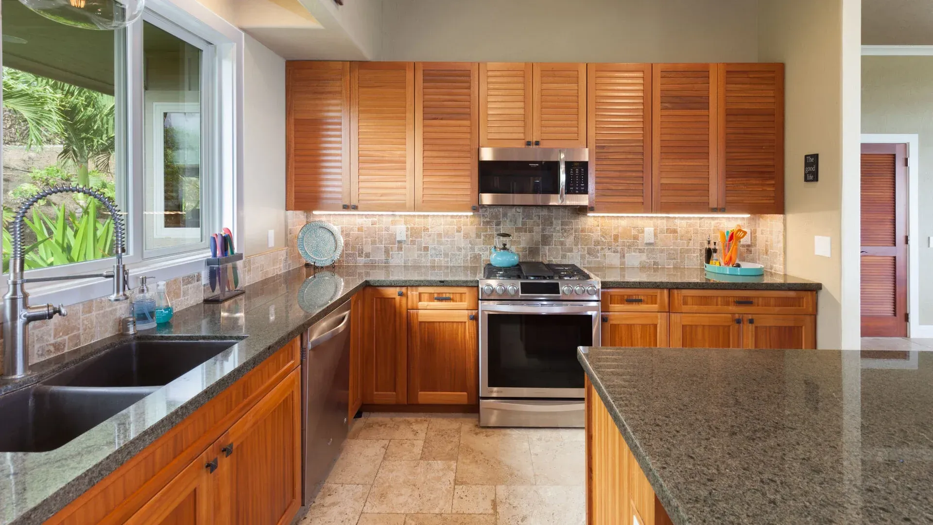 A kitchen with wooden cabinets , granite counter tops , stainless steel appliances and a sink.