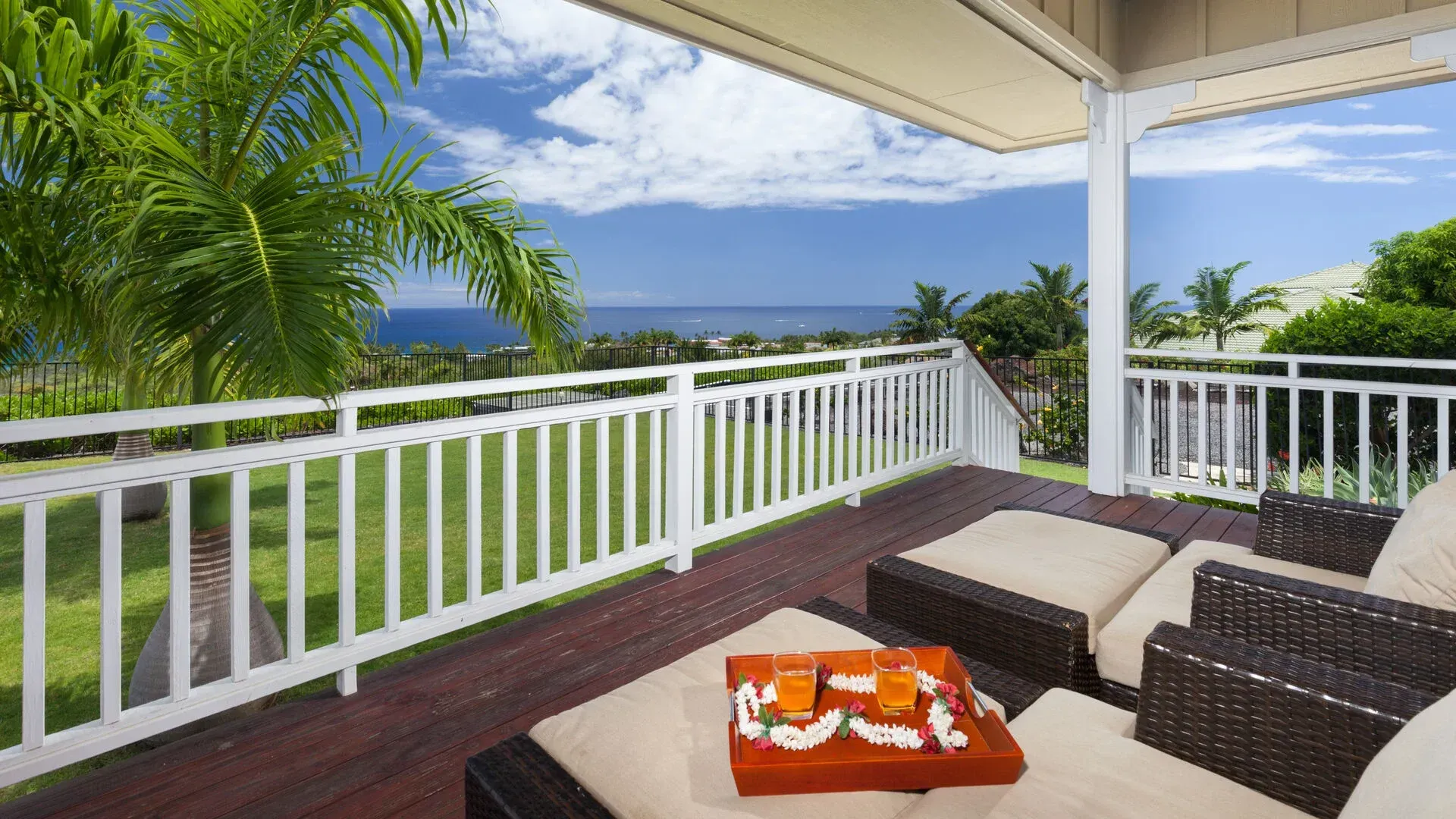 A balcony with a view of the ocean and palm trees