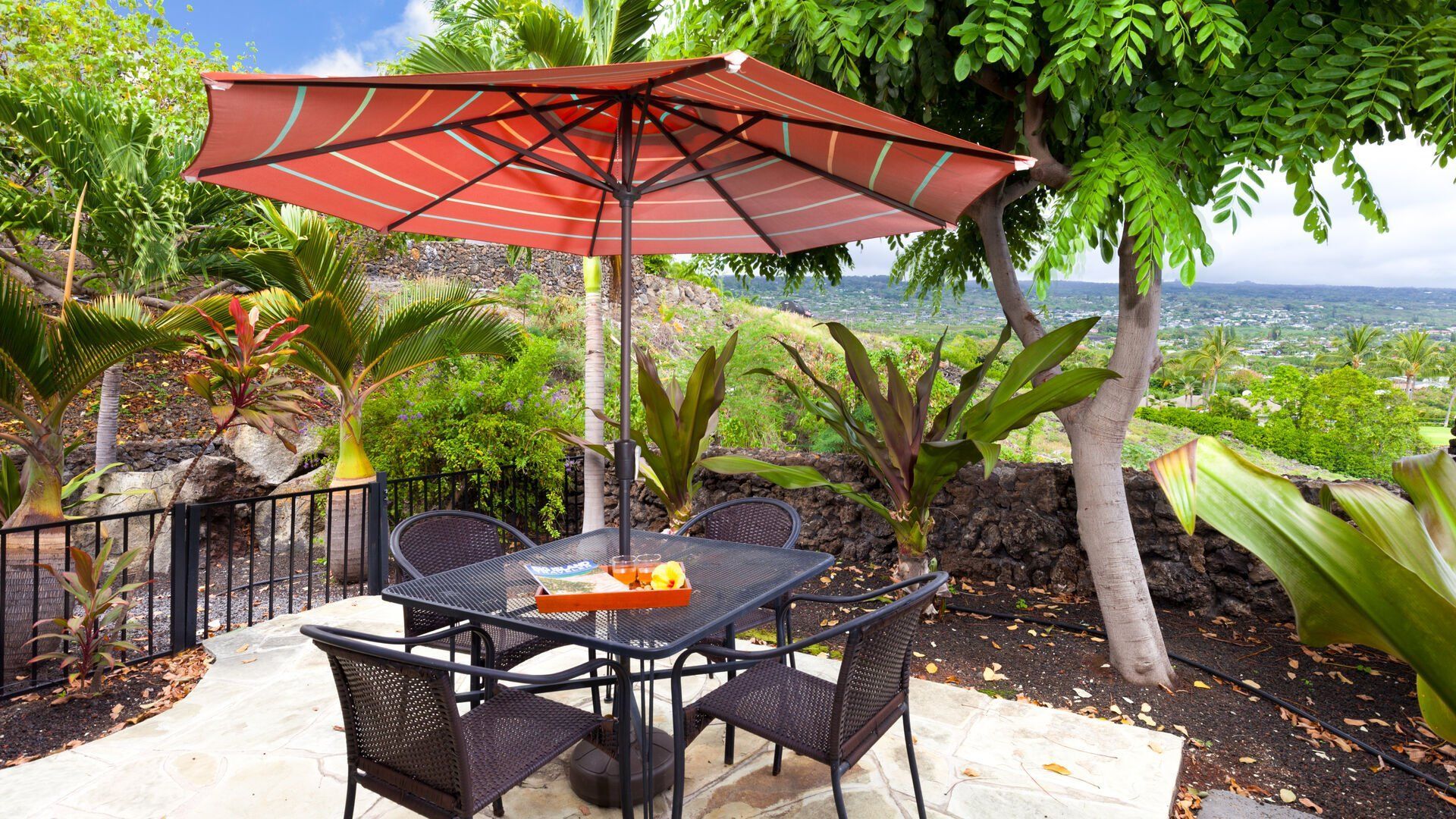 A patio with a table and chairs under an orange umbrella.