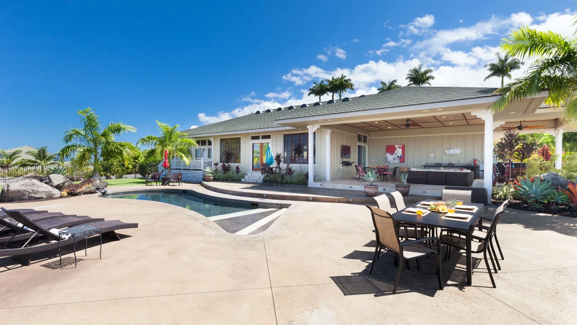 A large white house with a swimming pool and a table and chairs in front of it.