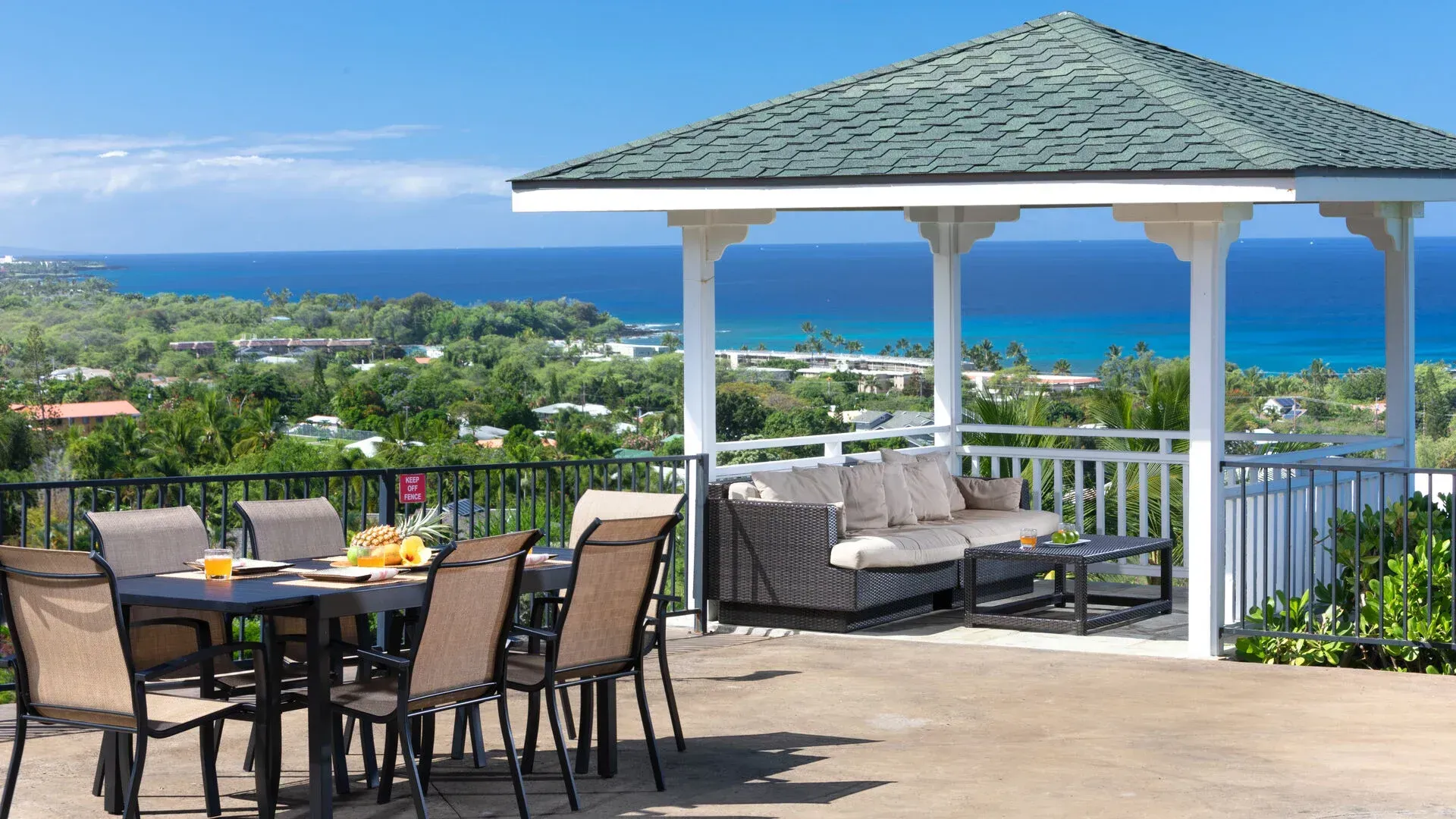 A gazebo with a table and chairs on it overlooking the ocean