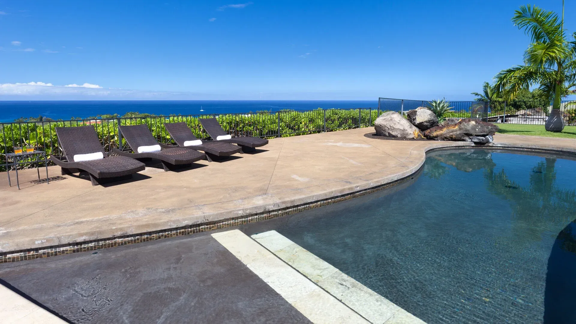A swimming pool with chairs and a view of the ocean