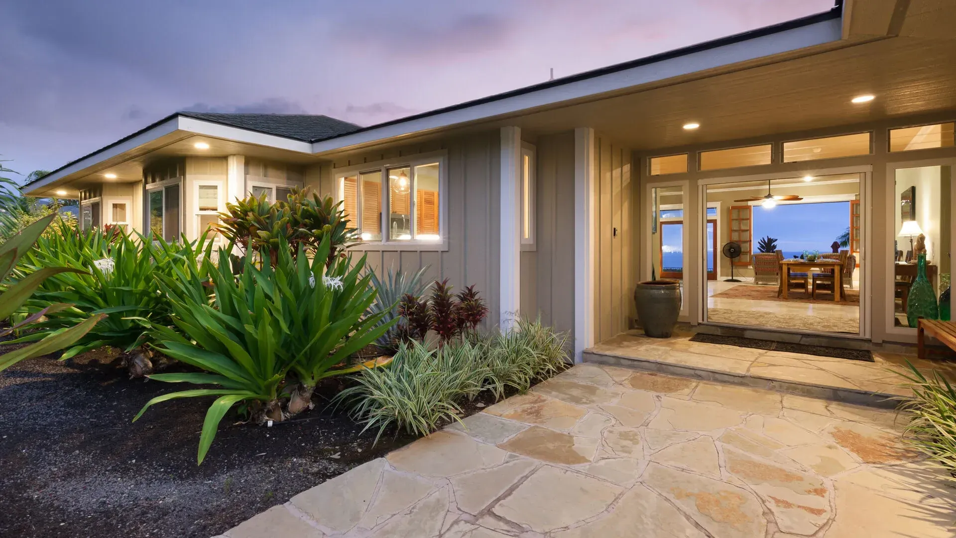 A large house with a lot of windows and plants in front of it.