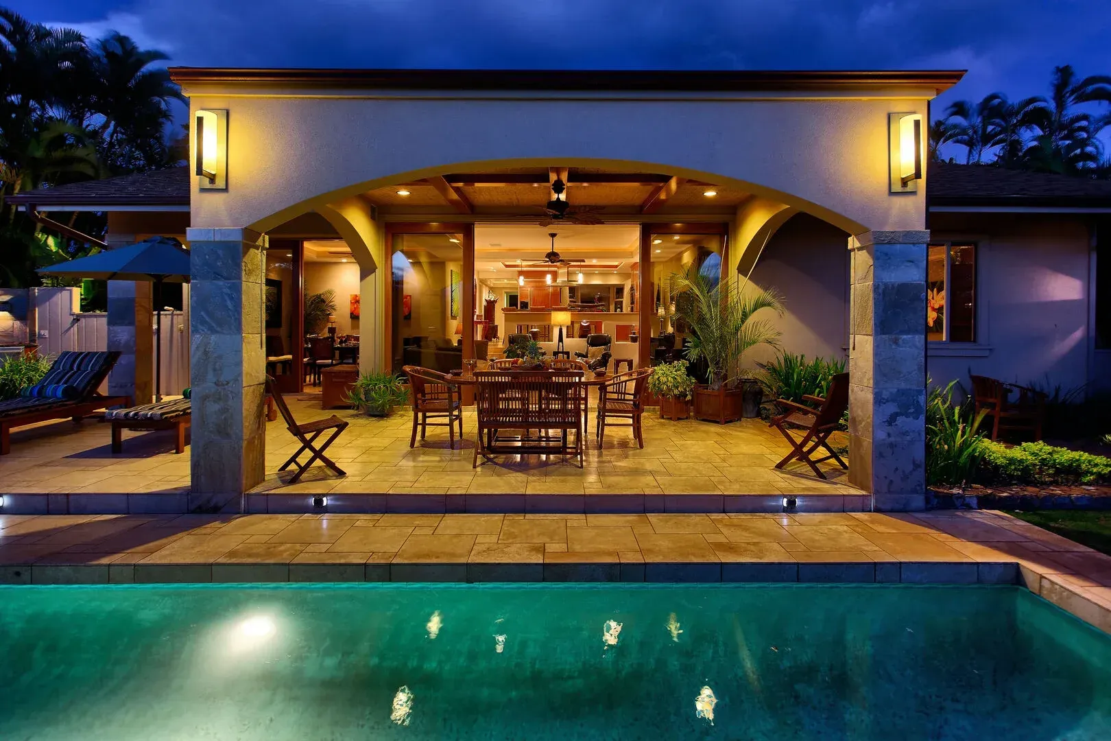 A house with a swimming pool and a patio at night