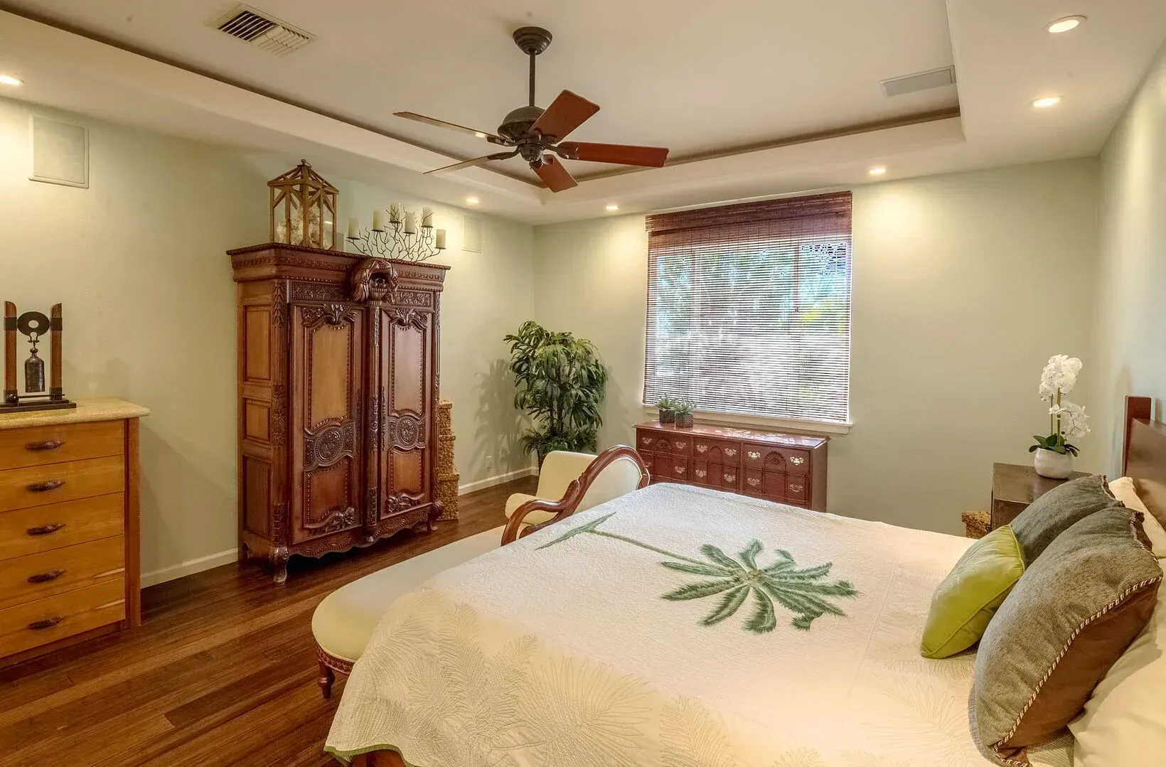 A bedroom with a bed , dresser , and ceiling fan