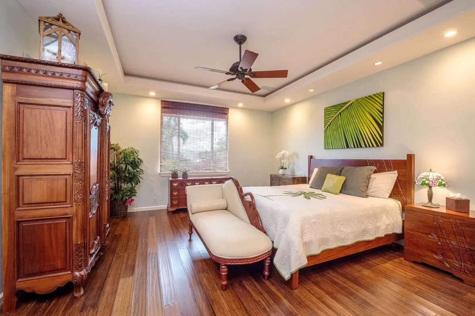 A bedroom with a large bed and a ceiling fan.