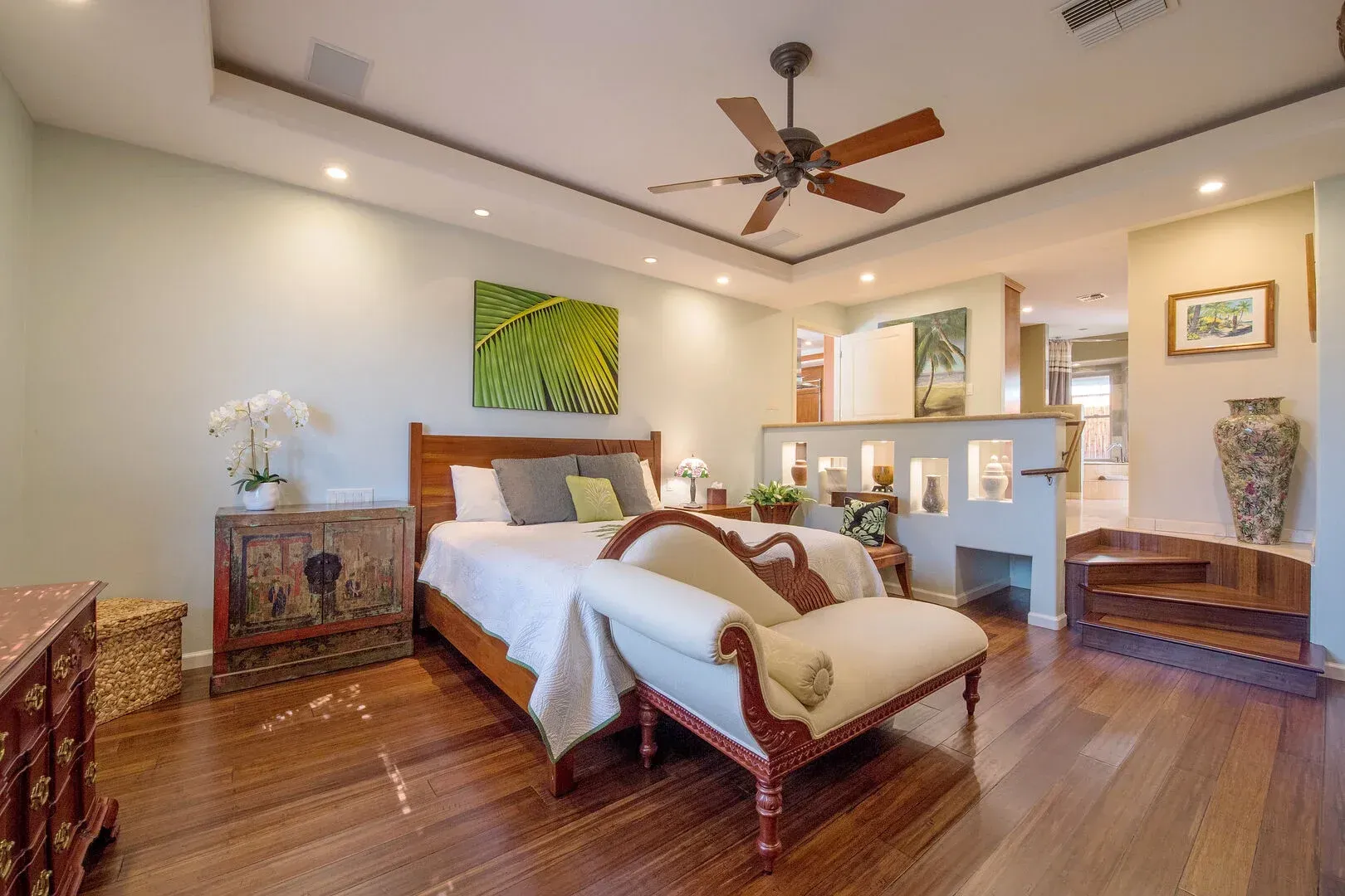A bedroom with a bed , chair , nightstand and ceiling fan.