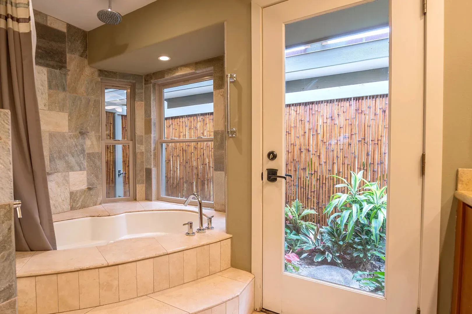 A bathroom with a jacuzzi tub and a glass door leading to a patio.