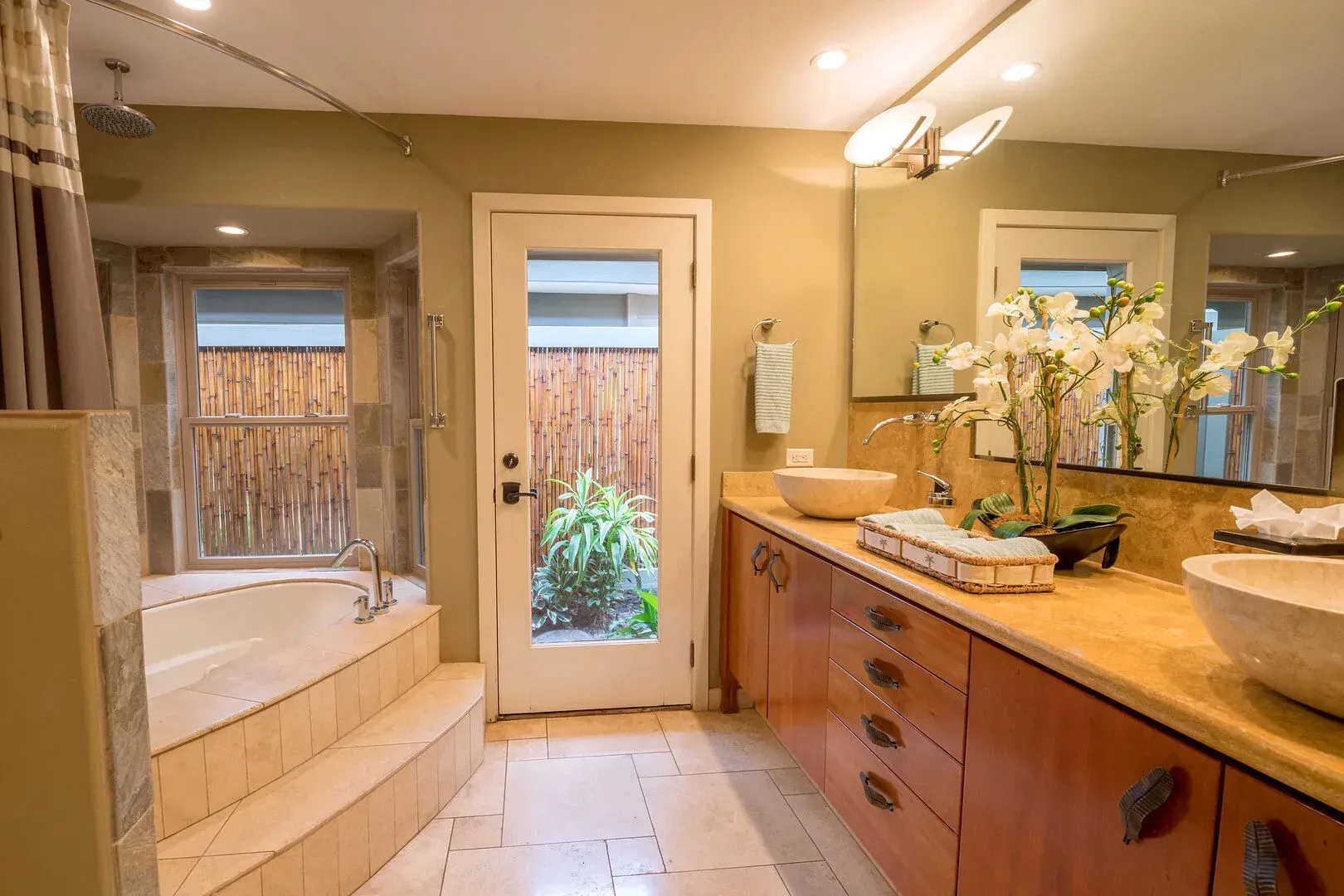A bathroom with a tub , sink , mirror and door.