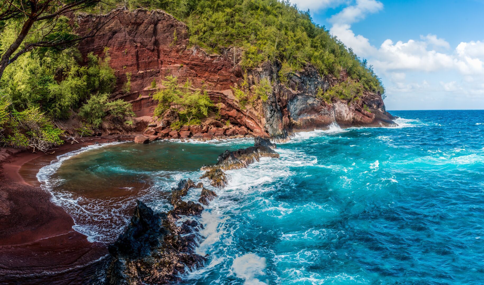 A cliff overlooking a body of water with waves crashing on the shore.