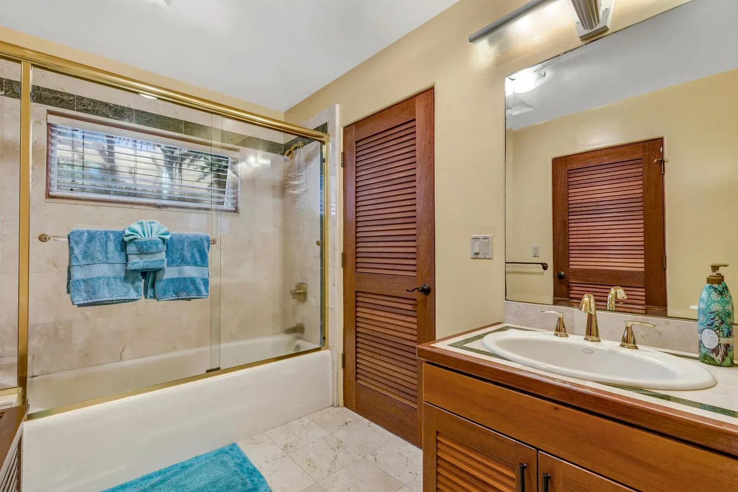 Bathroom with wood accents, shower, sink, and blue towels.