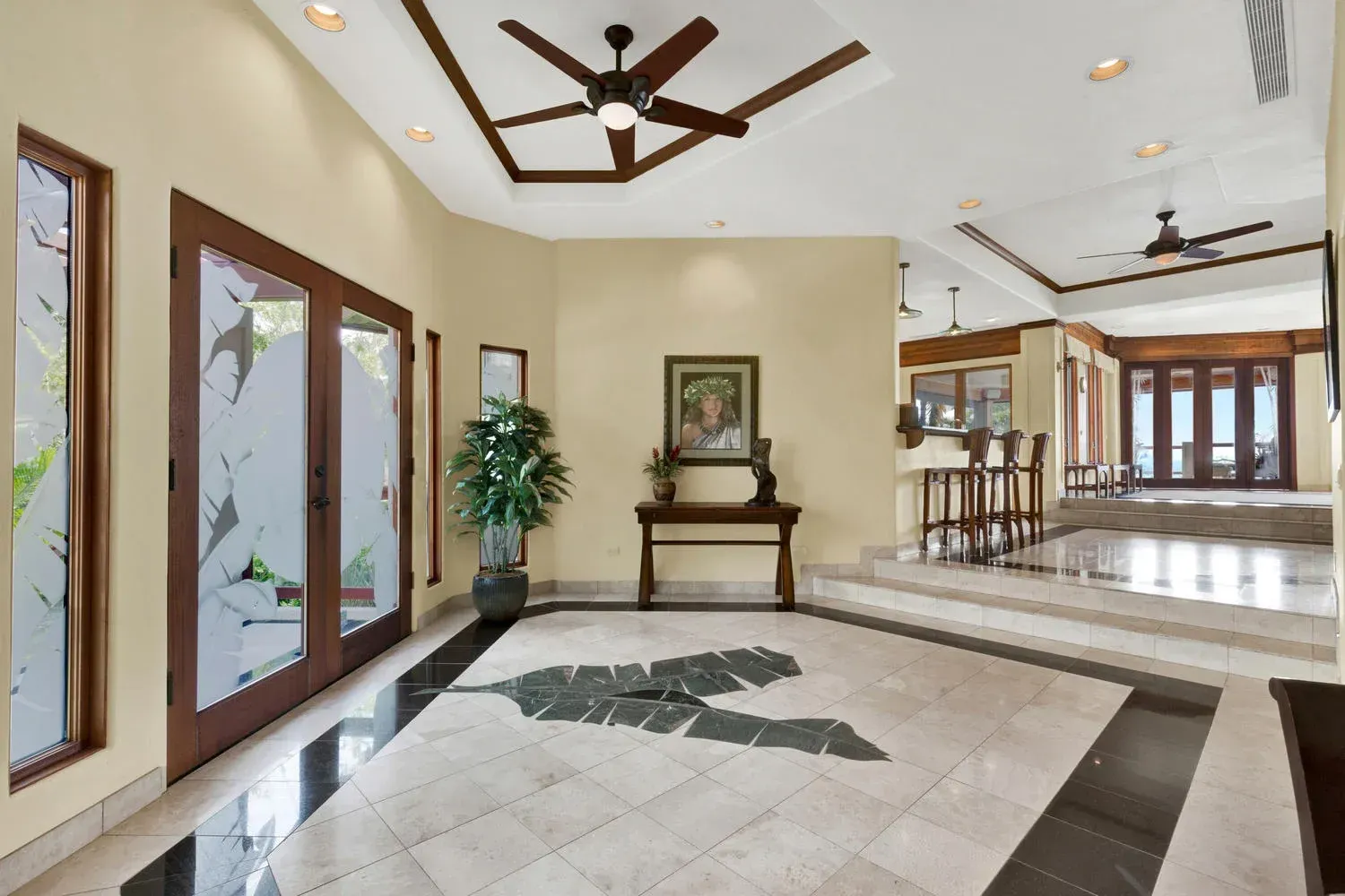 Spacious entryway with black and white tile, wooden trim, and doors leading outside.