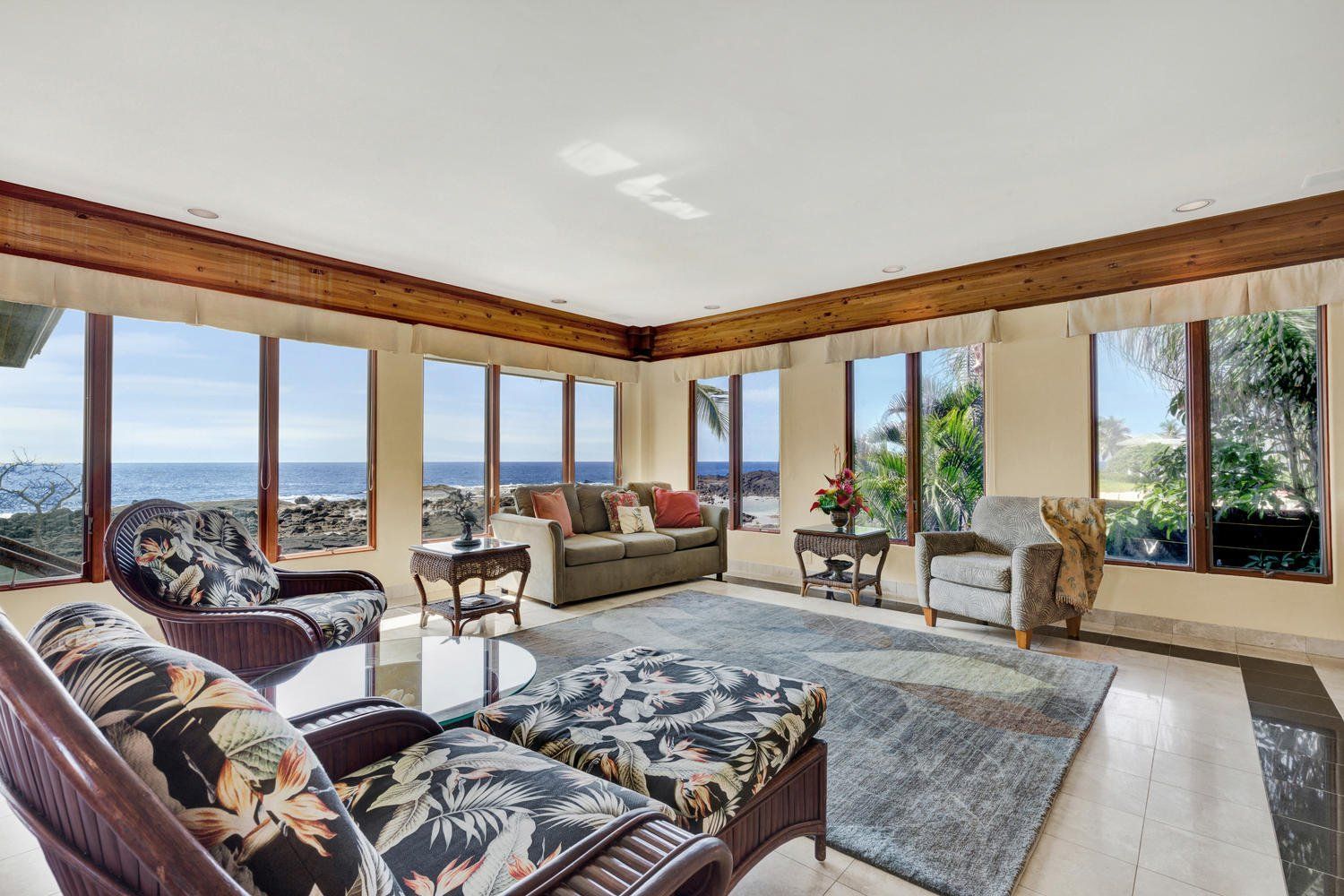 Living room with ocean view, featuring a sofa, chairs, and a rug.
