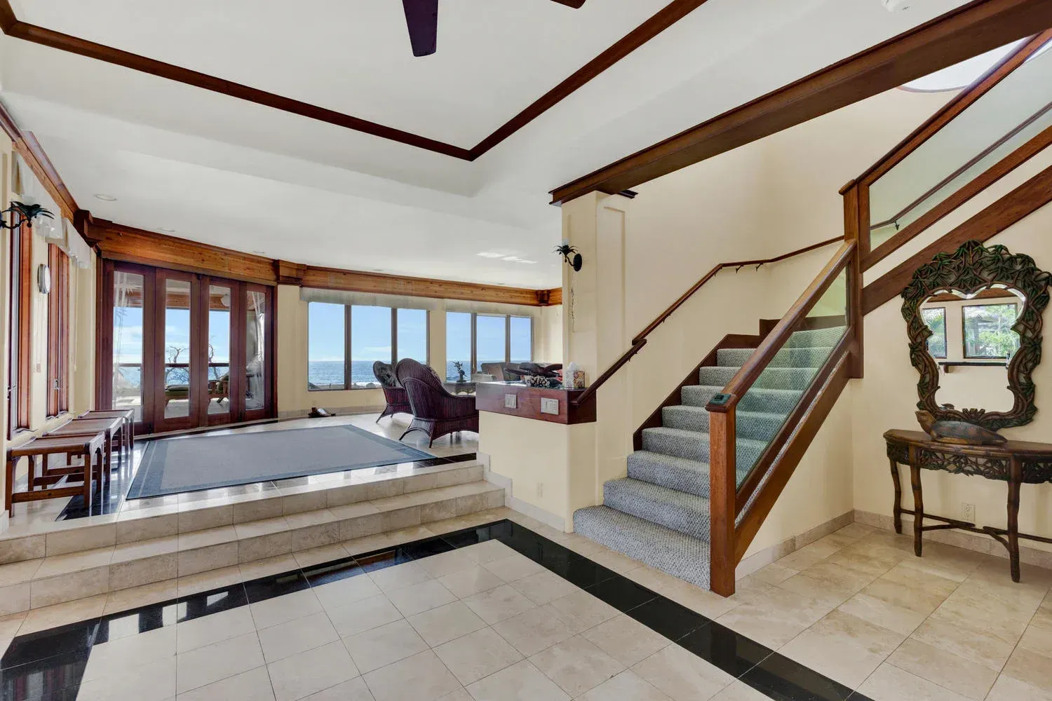 Spacious entryway with stairs, ocean view, and a decorative table with a mirror.