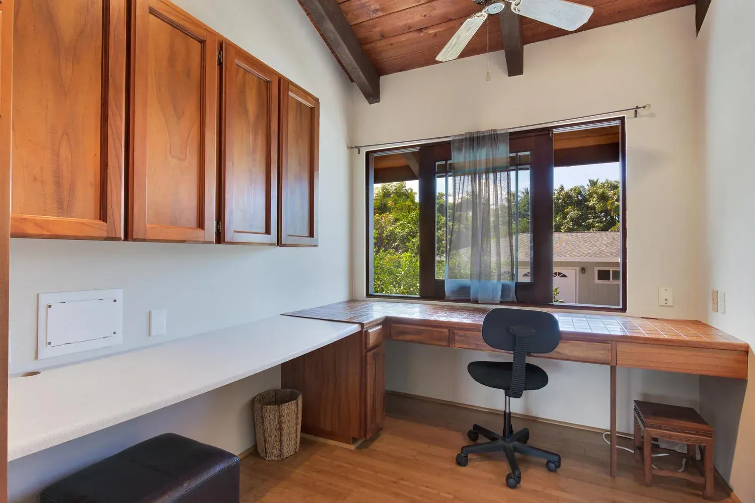 A room with a desk and a chair and a ceiling fan.