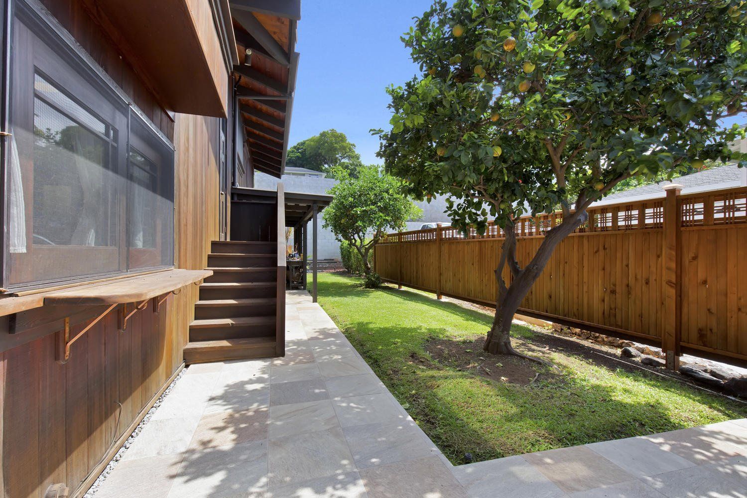 The backyard of a house with a wooden fence and a tree.
