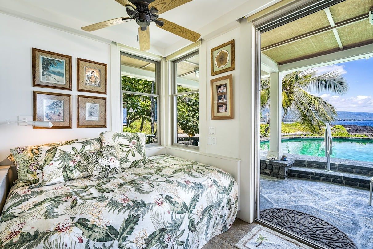 A bedroom with a bed and a ceiling fan next to a pool.
