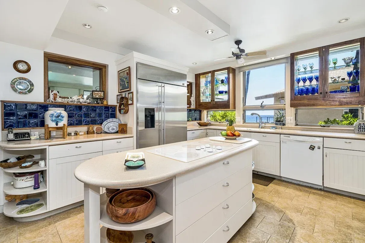 A kitchen with white cabinets , stainless steel appliances and a large island.