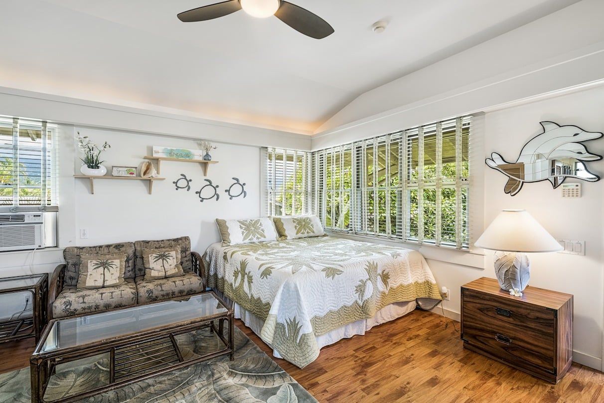A bedroom with a bed , couch , nightstand and ceiling fan.