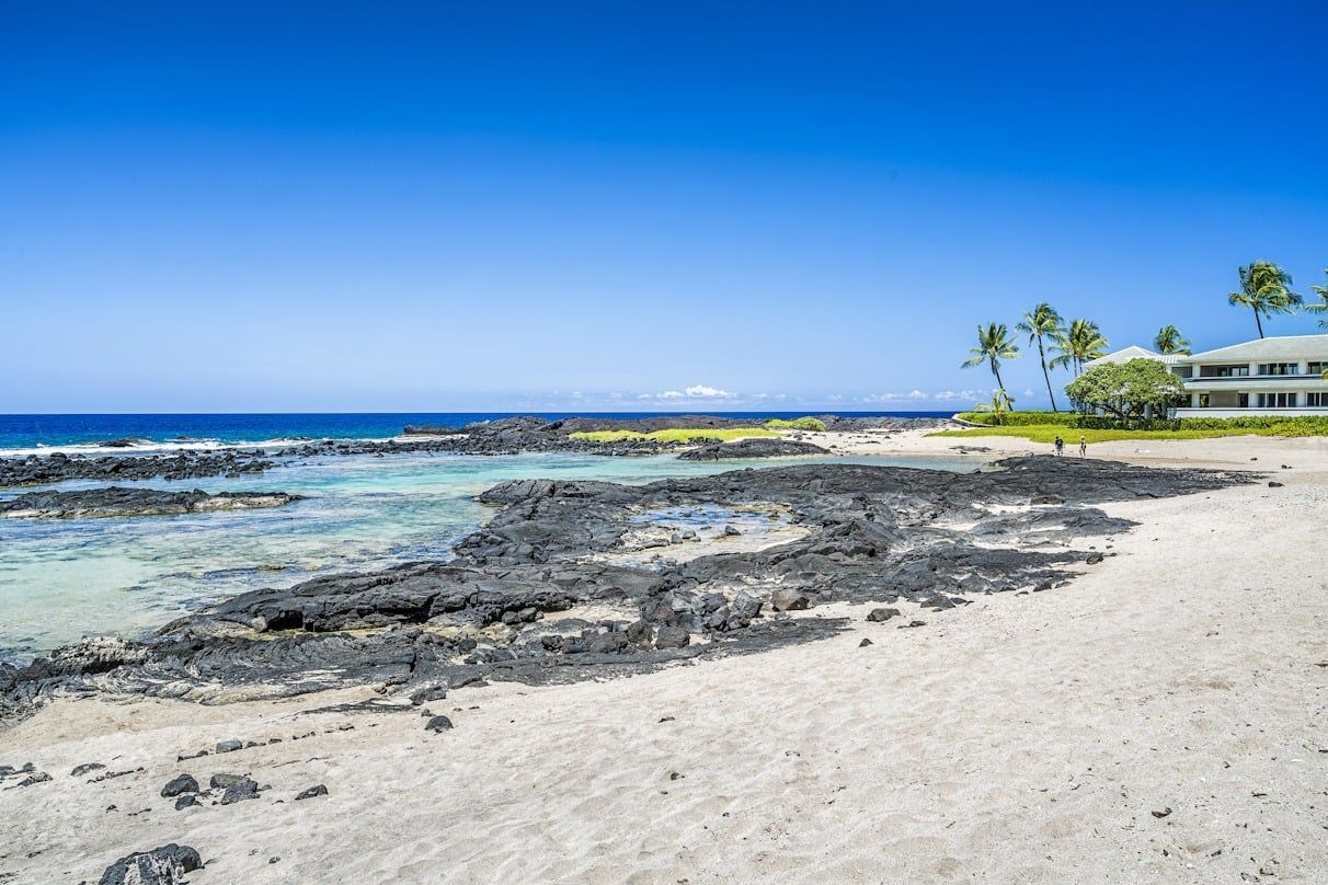 A beach with a house in the background and a large body of water.