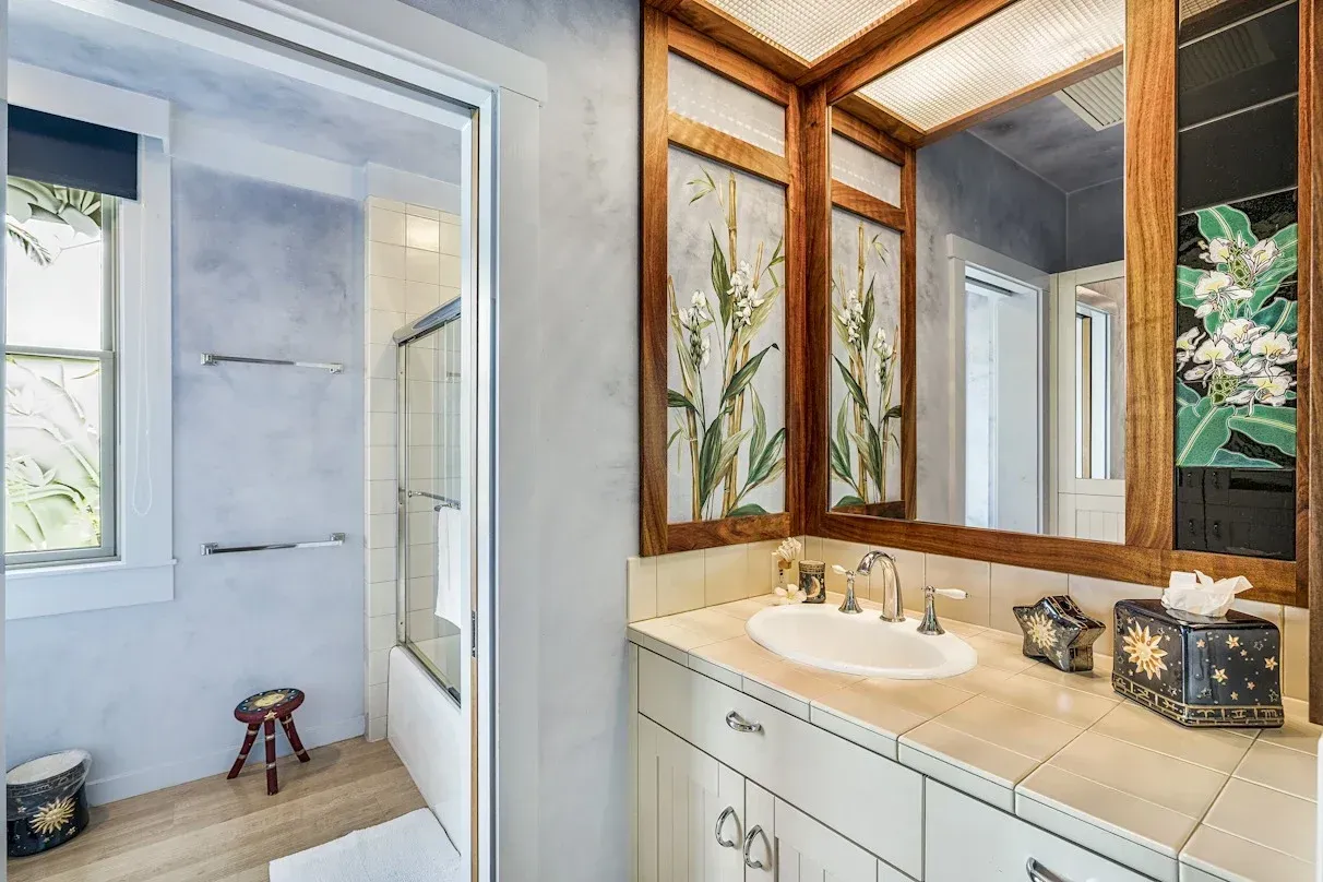 A bathroom with a sink , mirror and shower.