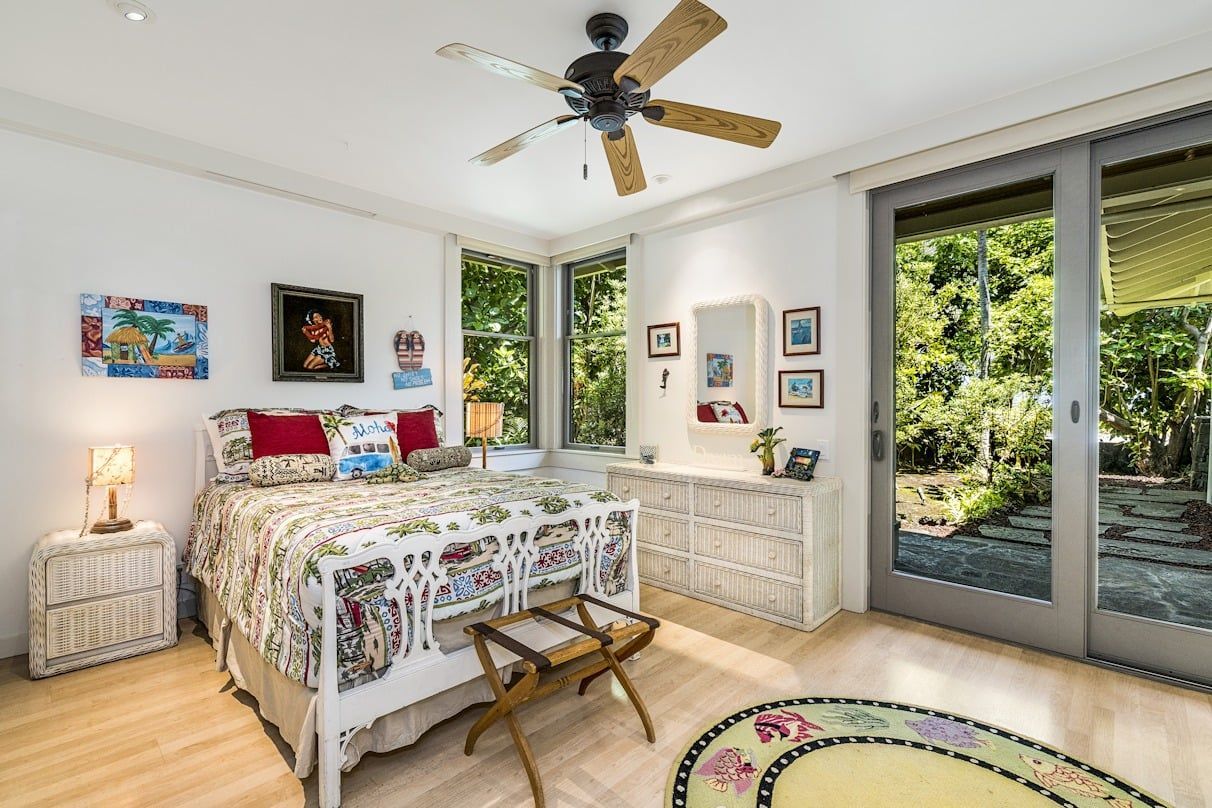 A bedroom with a bed , nightstand , ceiling fan and sliding glass doors.