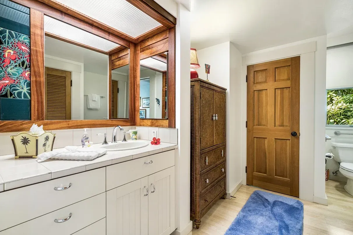 A bathroom with two sinks , two mirrors and a blue rug.