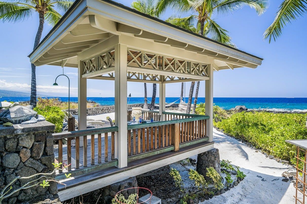 There is a gazebo on the beach with a view of the ocean.