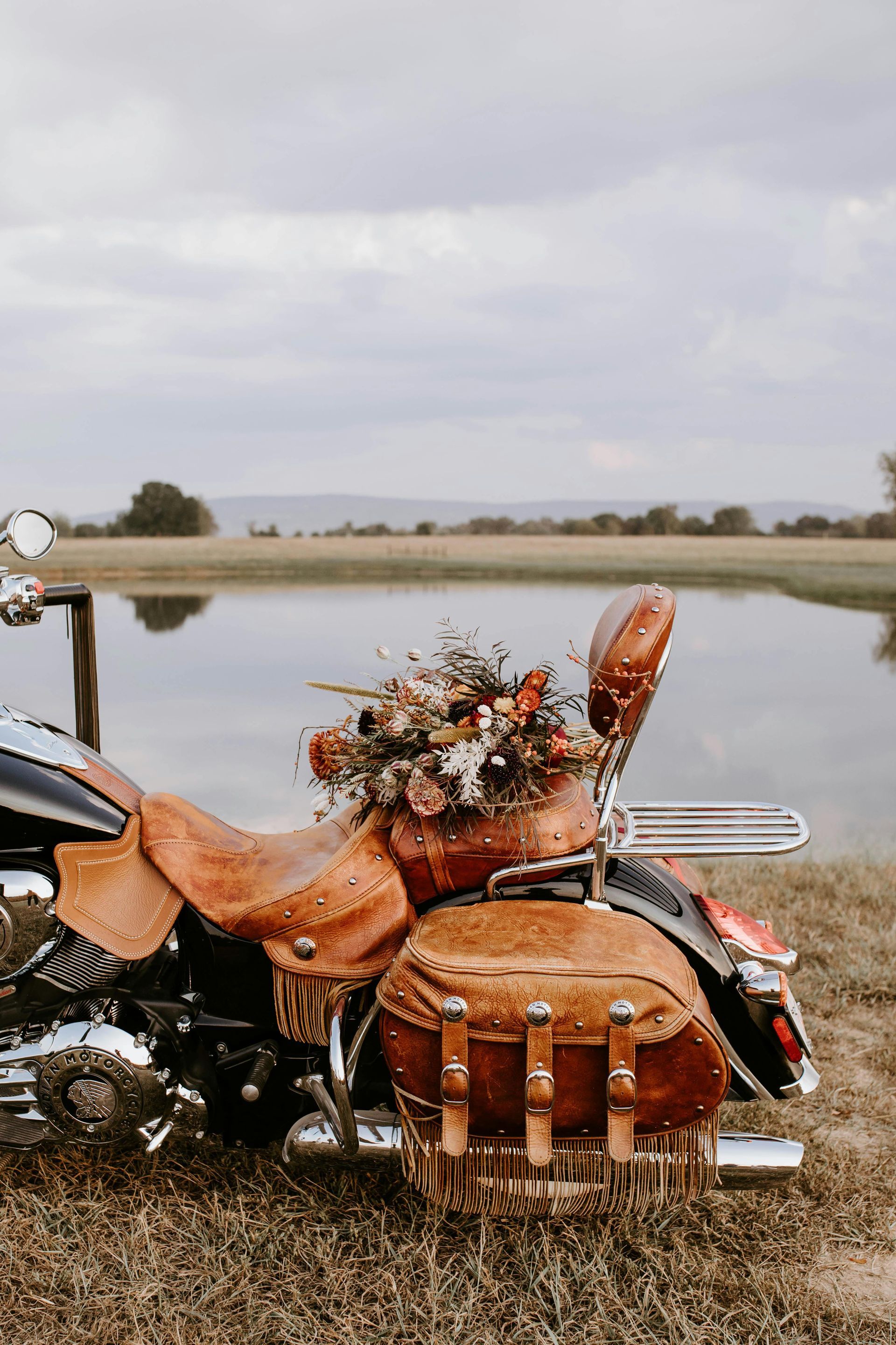 A motorcycle is parked in the grass next to a body of water.