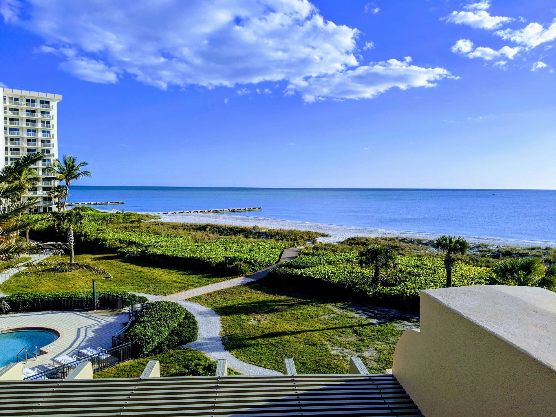 A view of the ocean from a balcony with a building in the background.