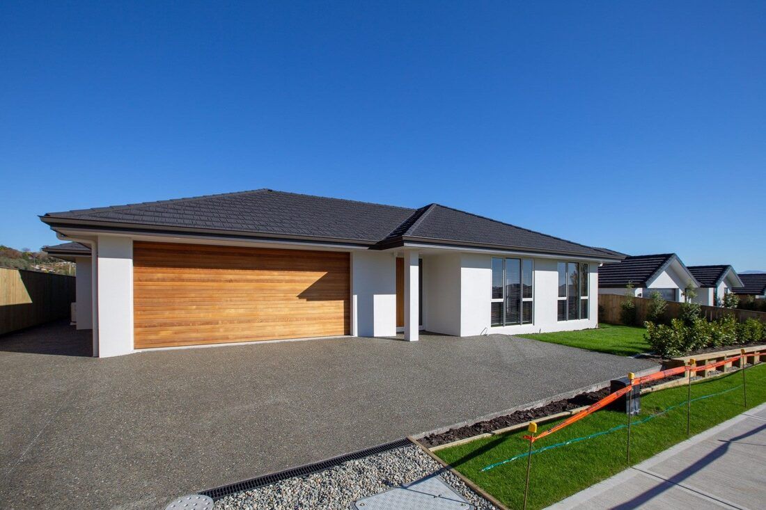 A white house with a wooden garage door and a concrete driveway.