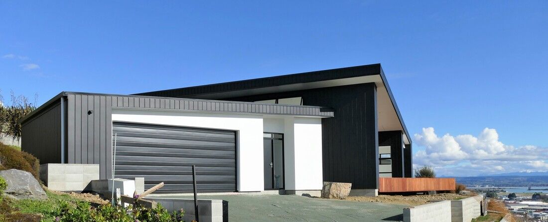 A house is sitting on top of a hill with a blue sky in the background.