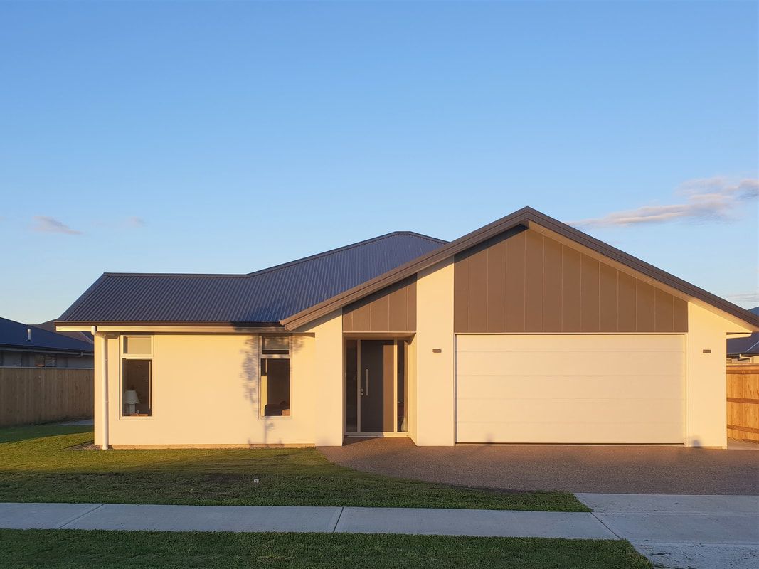 A white house with a brown roof and a driveway