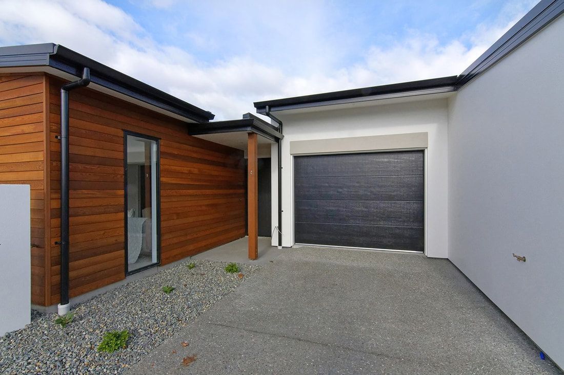 A modern house with a garage and wooden siding.