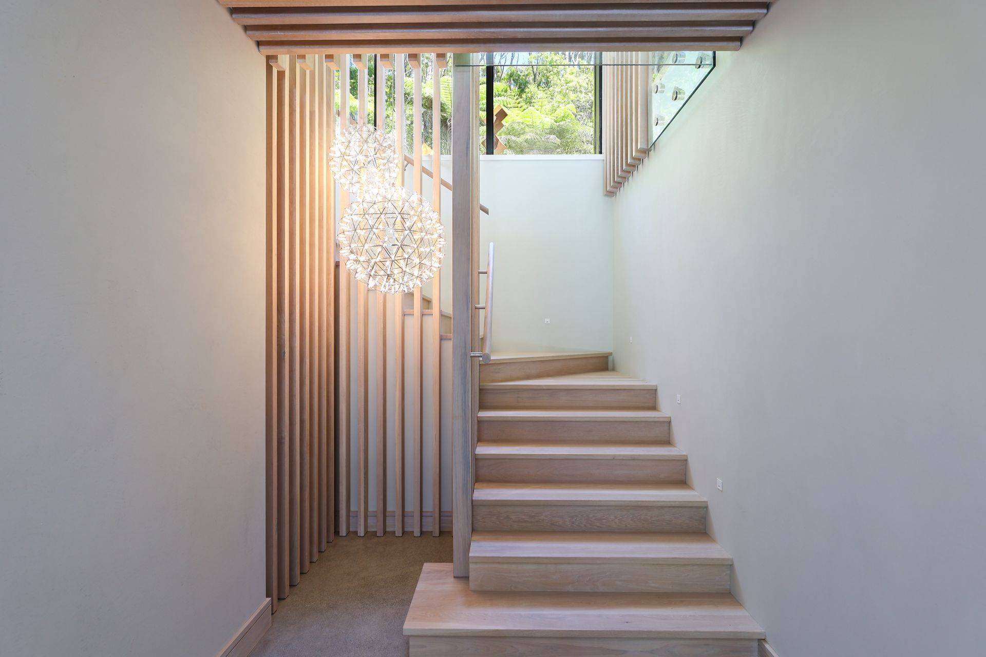 A staircase in a house with a chandelier hanging from the ceiling.