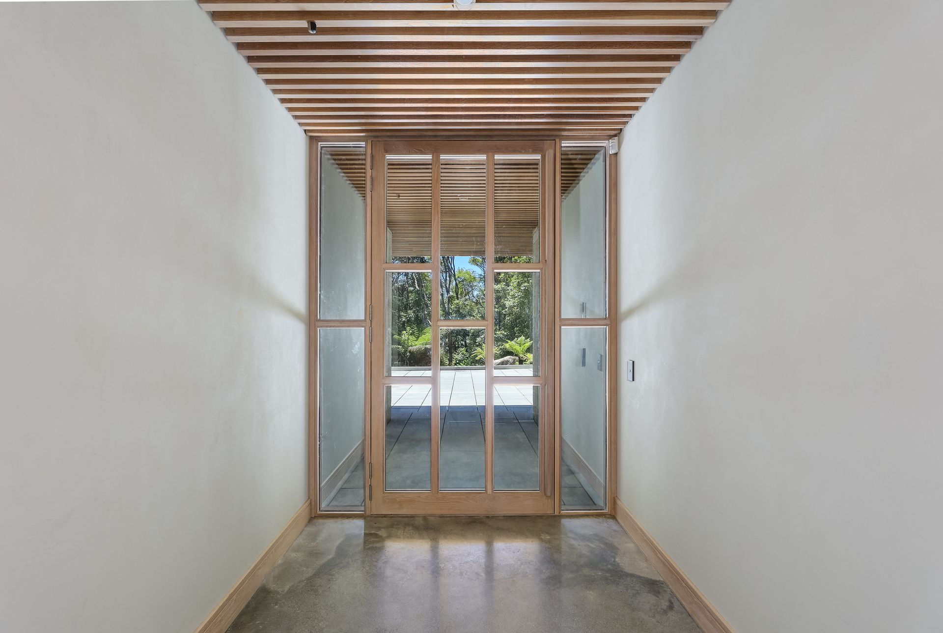 A hallway with a sliding glass door and a wooden ceiling.