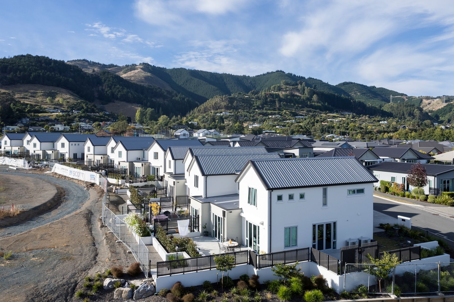 An aerial view of a residential area with houses and mountains in the background.