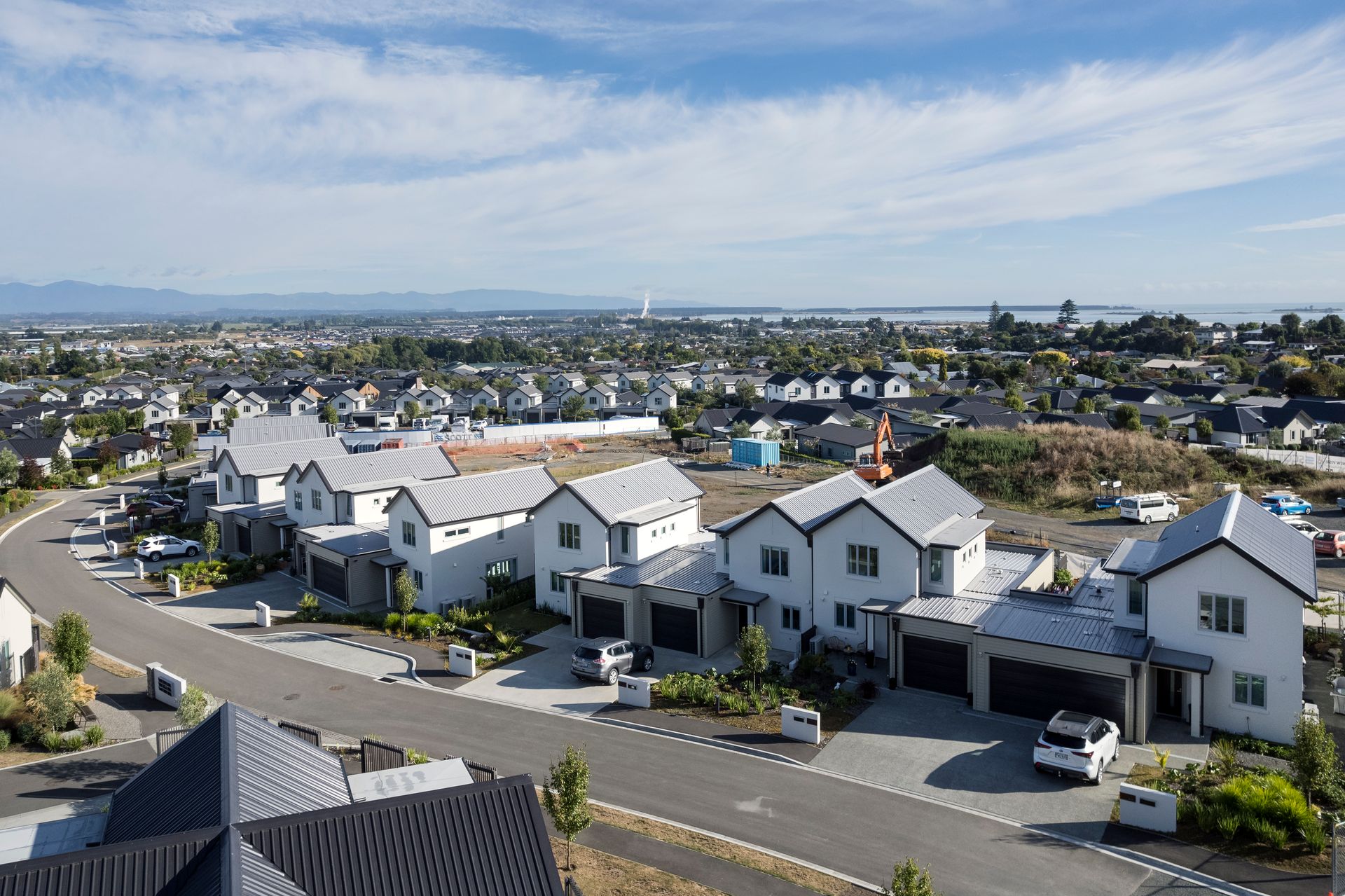 An aerial view of a residential area with lots of houses and cars parked on the side of the road.