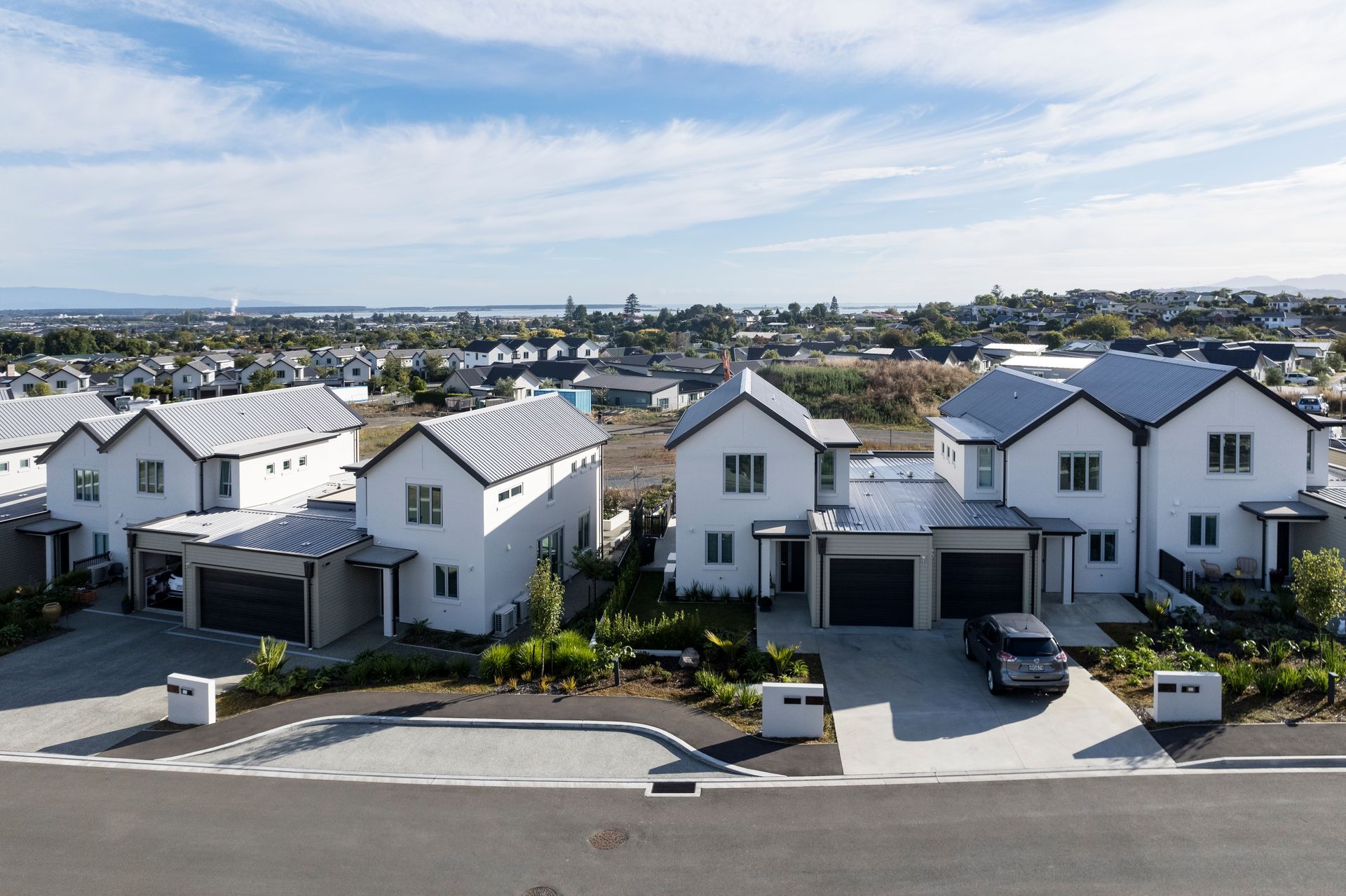 An aerial view of a row of houses with cars parked in front of them