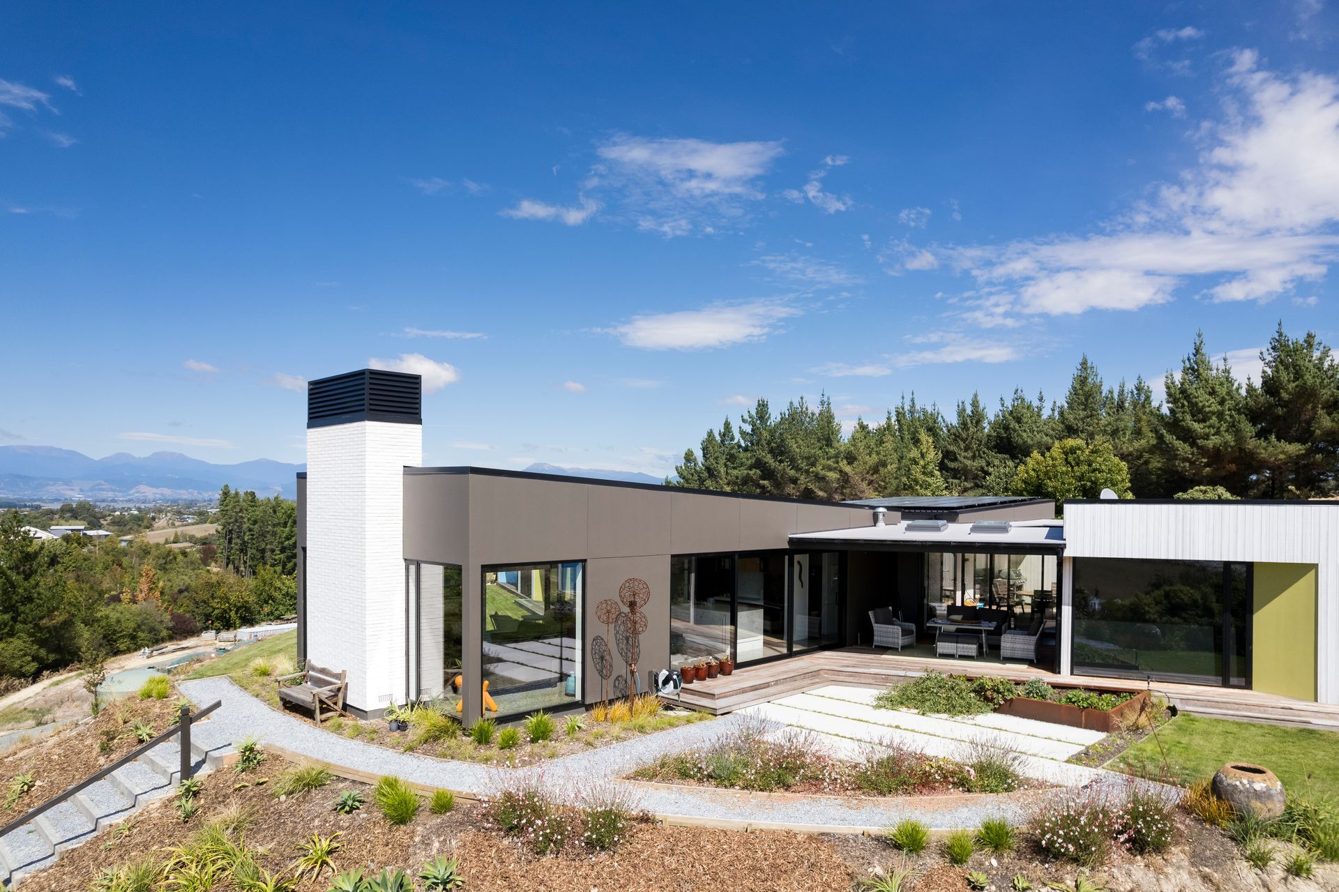 A modern house with a lot of windows is surrounded by trees.