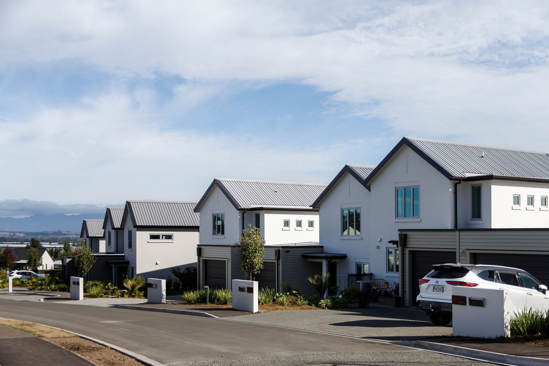 A row of houses with cars parked in front of them on a sunny day.