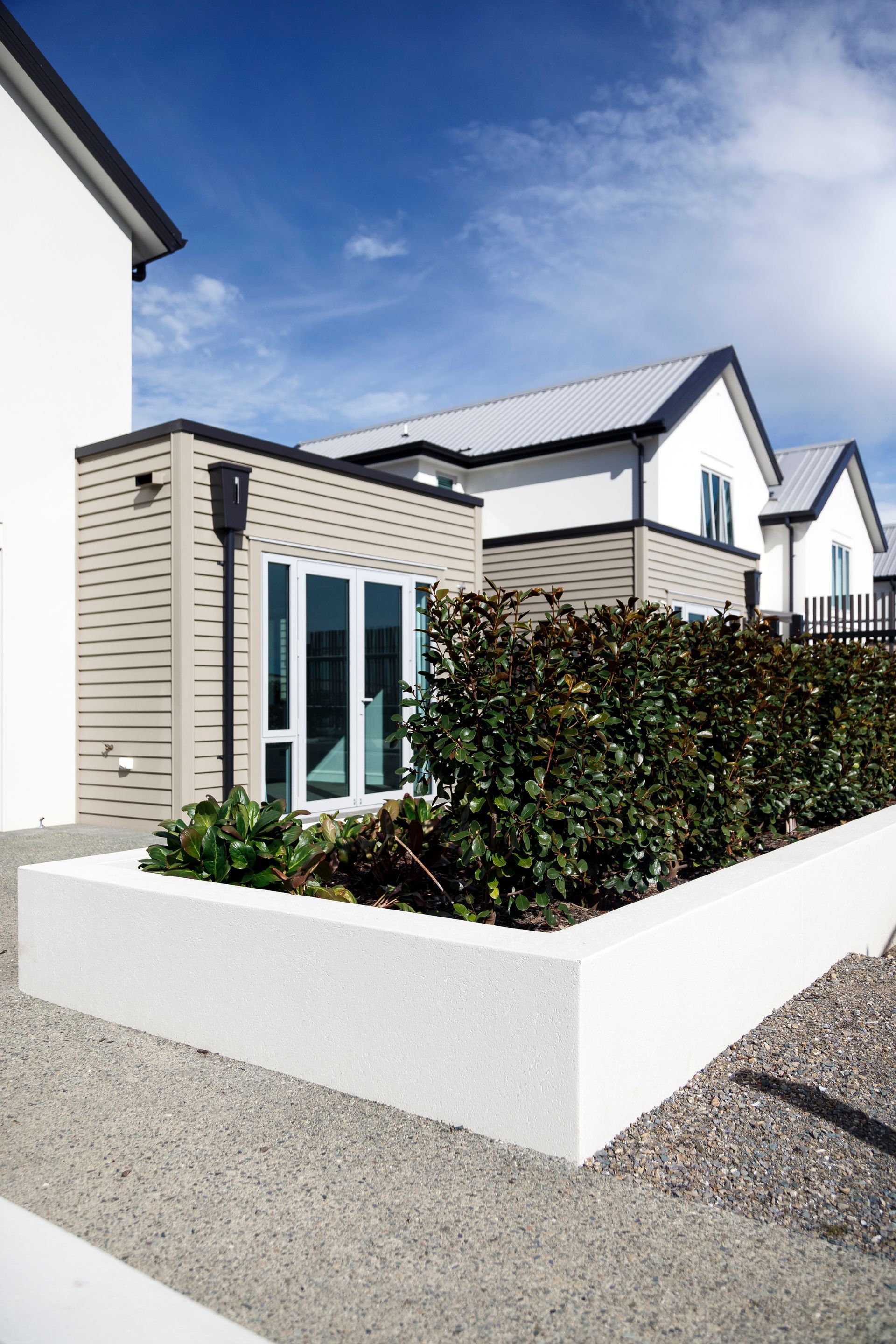 A white house with a planter in front of it.